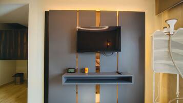 Una sala de estar moderna con un televisor de pantalla plana montado en una pared, un estante pequeño debajo y una tira de luces decorativa.
