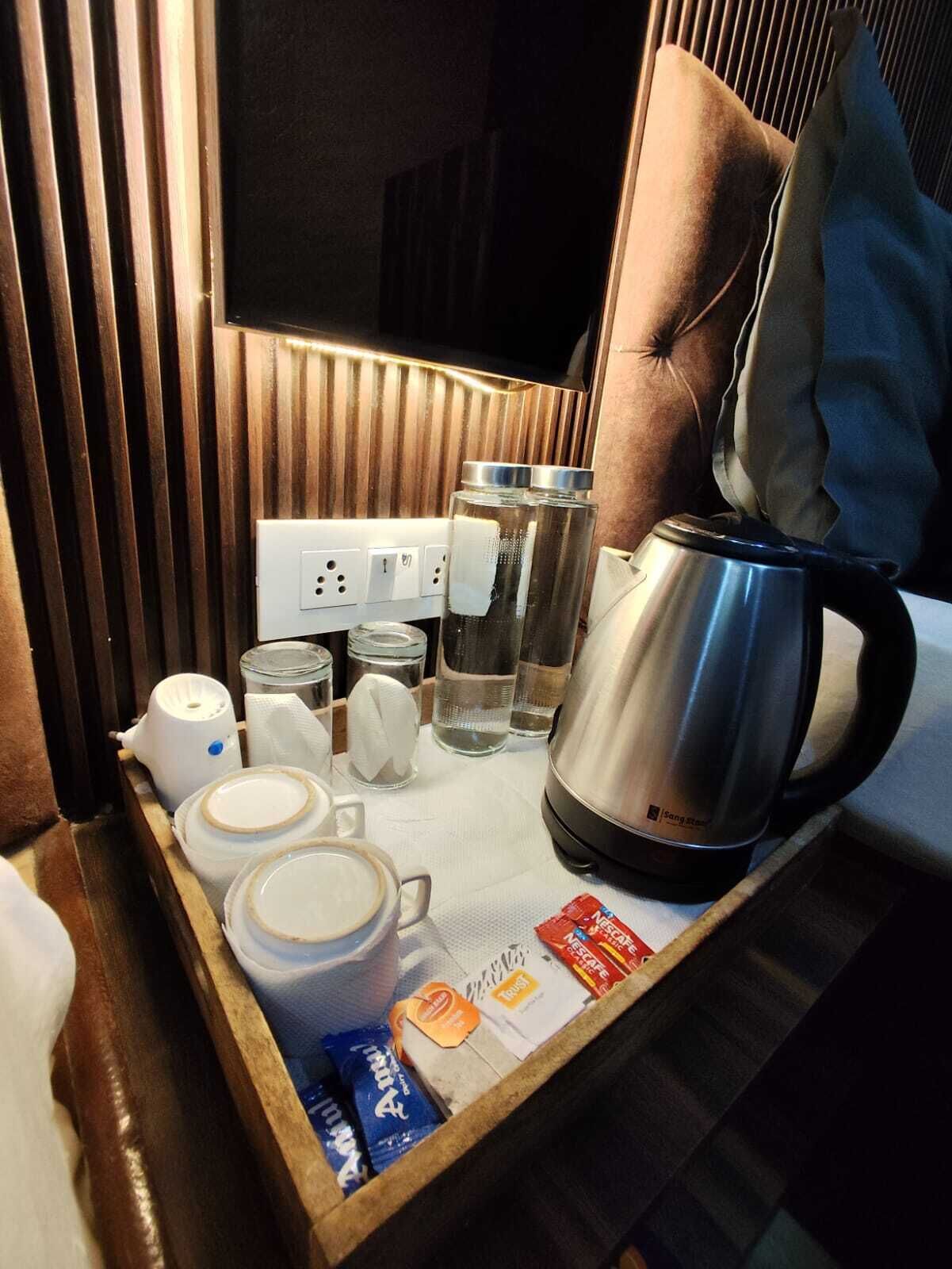 A tray with a coffee maker, cups, a tissue, a bottle of water, and a box of coffee creamer.