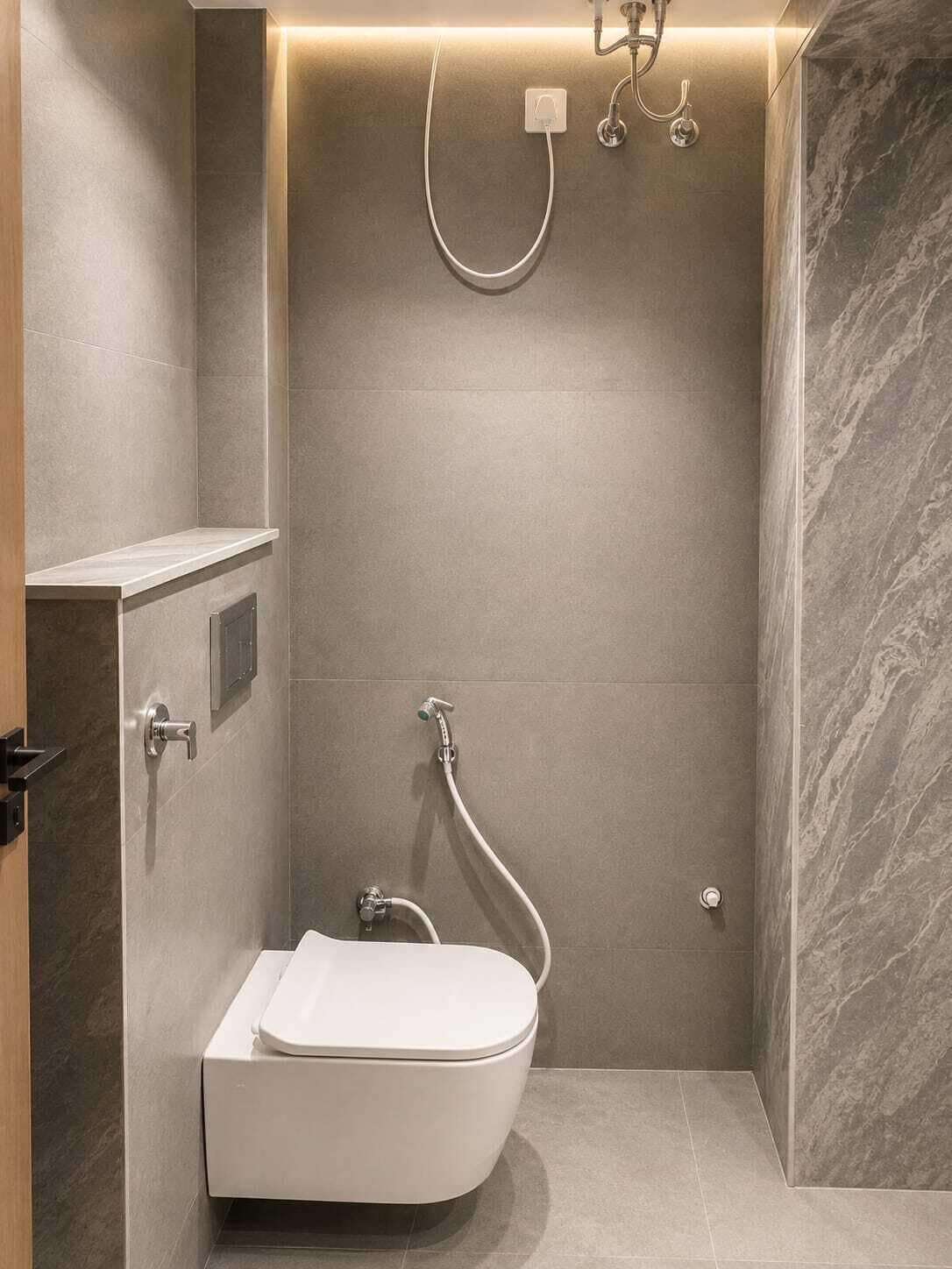 A modern bathroom with a built-in toilet, a shower with a handheld showerhead, and a wall-mounted faucet.