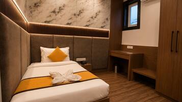A hotel room with a bed, a desk, and a wardrobe.
