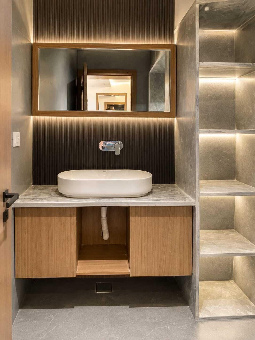 A modern bathroom with a built-in sink, mirror, and illuminated shelves.
