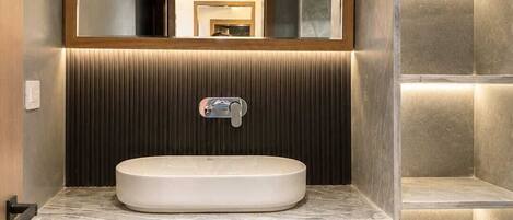 A modern bathroom with a built-in sink, mirror, and illuminated shelves.