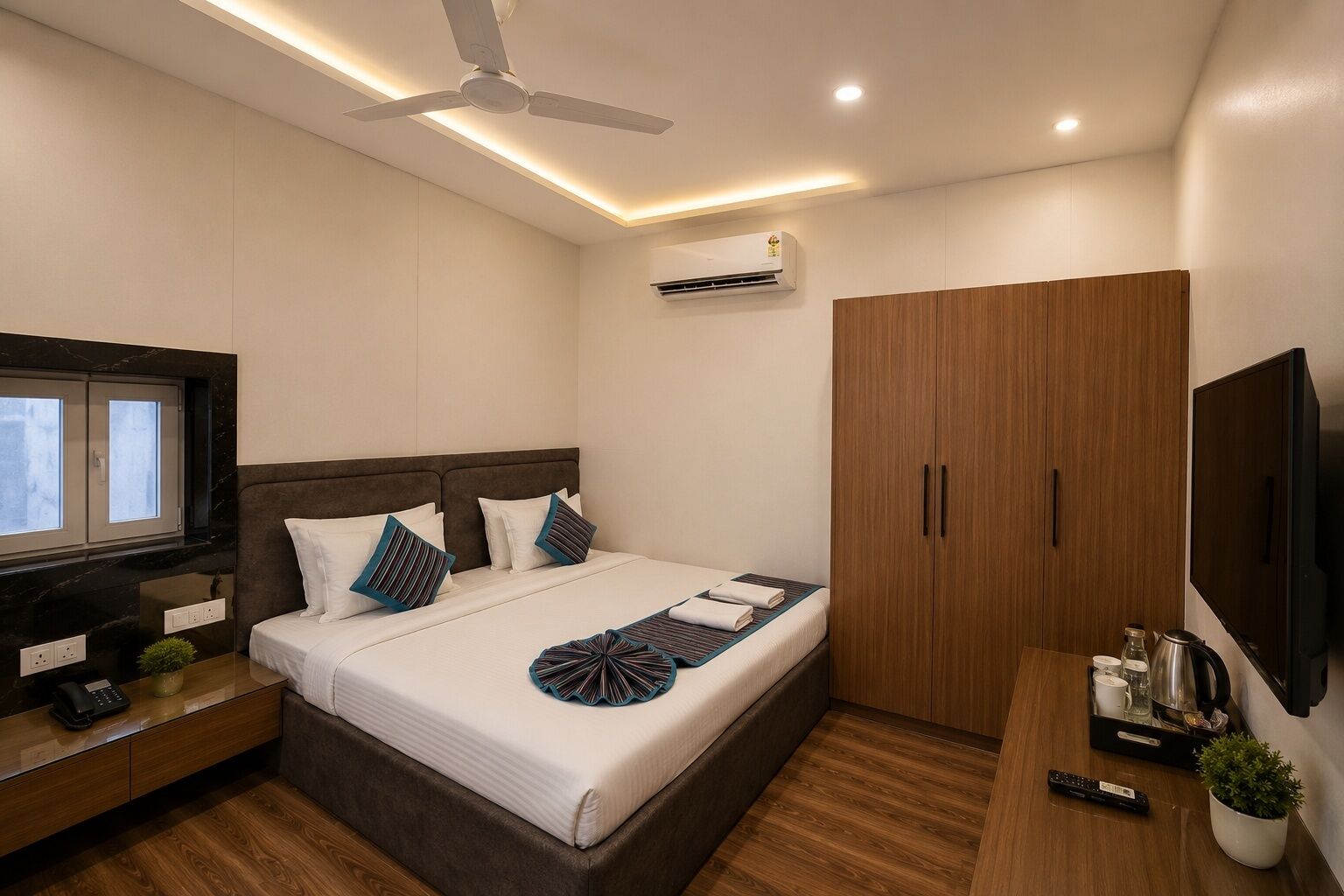 Ein modernes Hotelzimmer mit Bett, Fernseher, Kleiderschrank und Schreibtisch mit Pflanze.