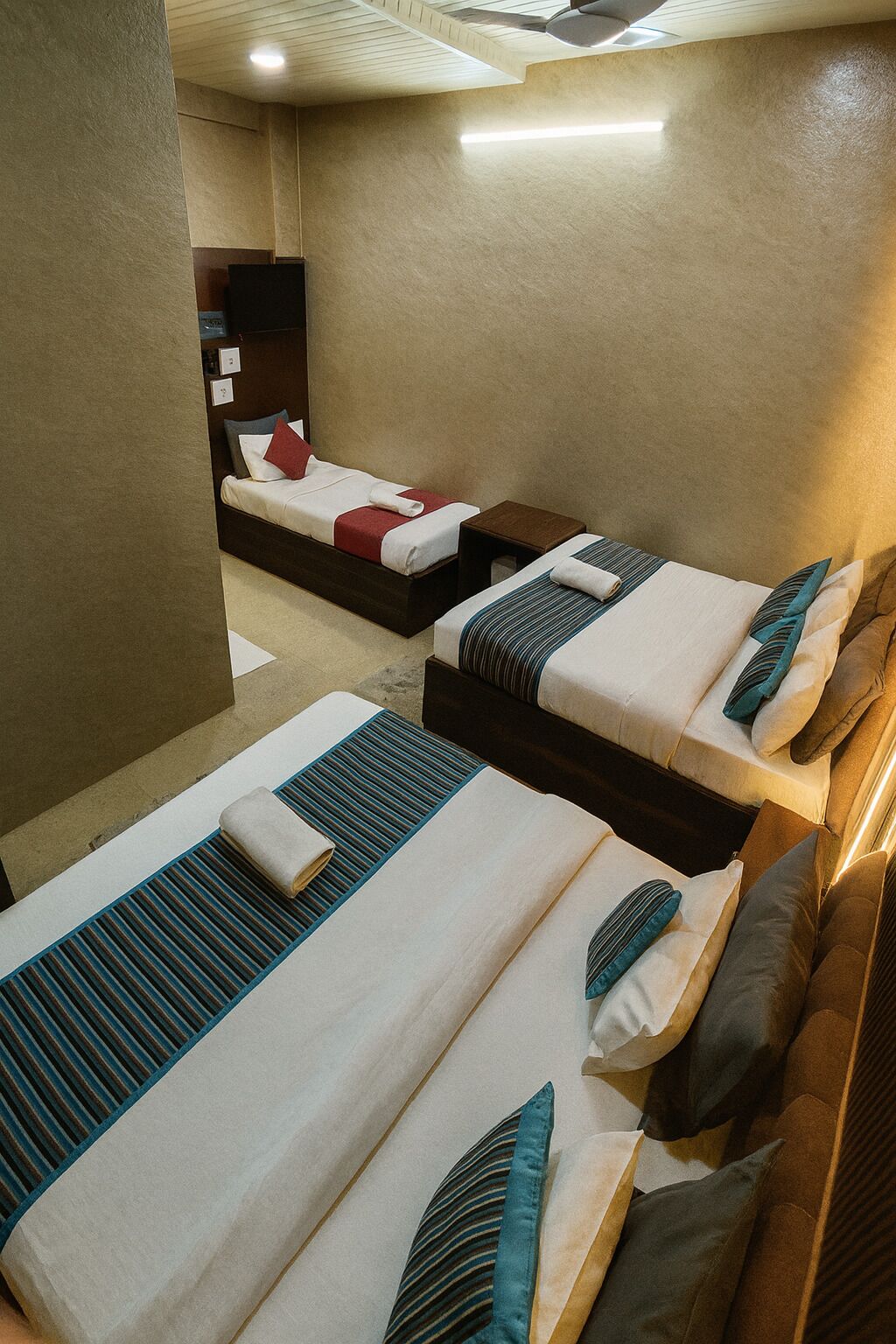 A hotel room with two beds, each with a pillow and a blanket. There is a small table and a chair in the room.