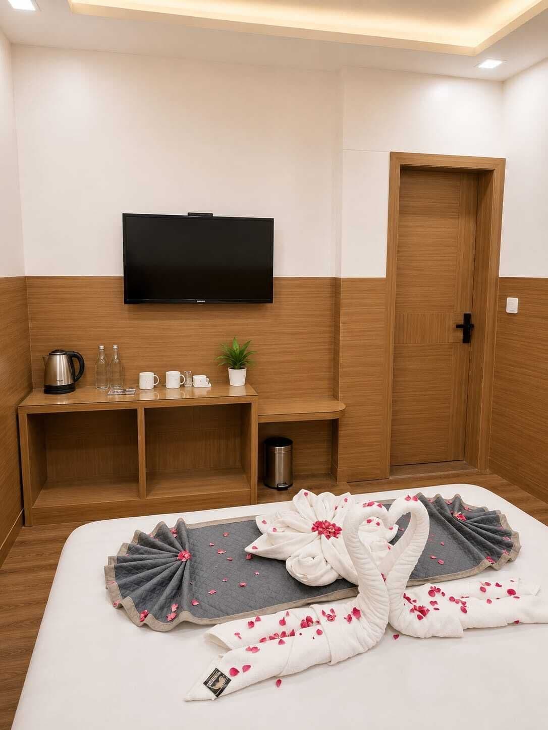A hotel room with a bed, a TV, a wooden cabinet, and a door.