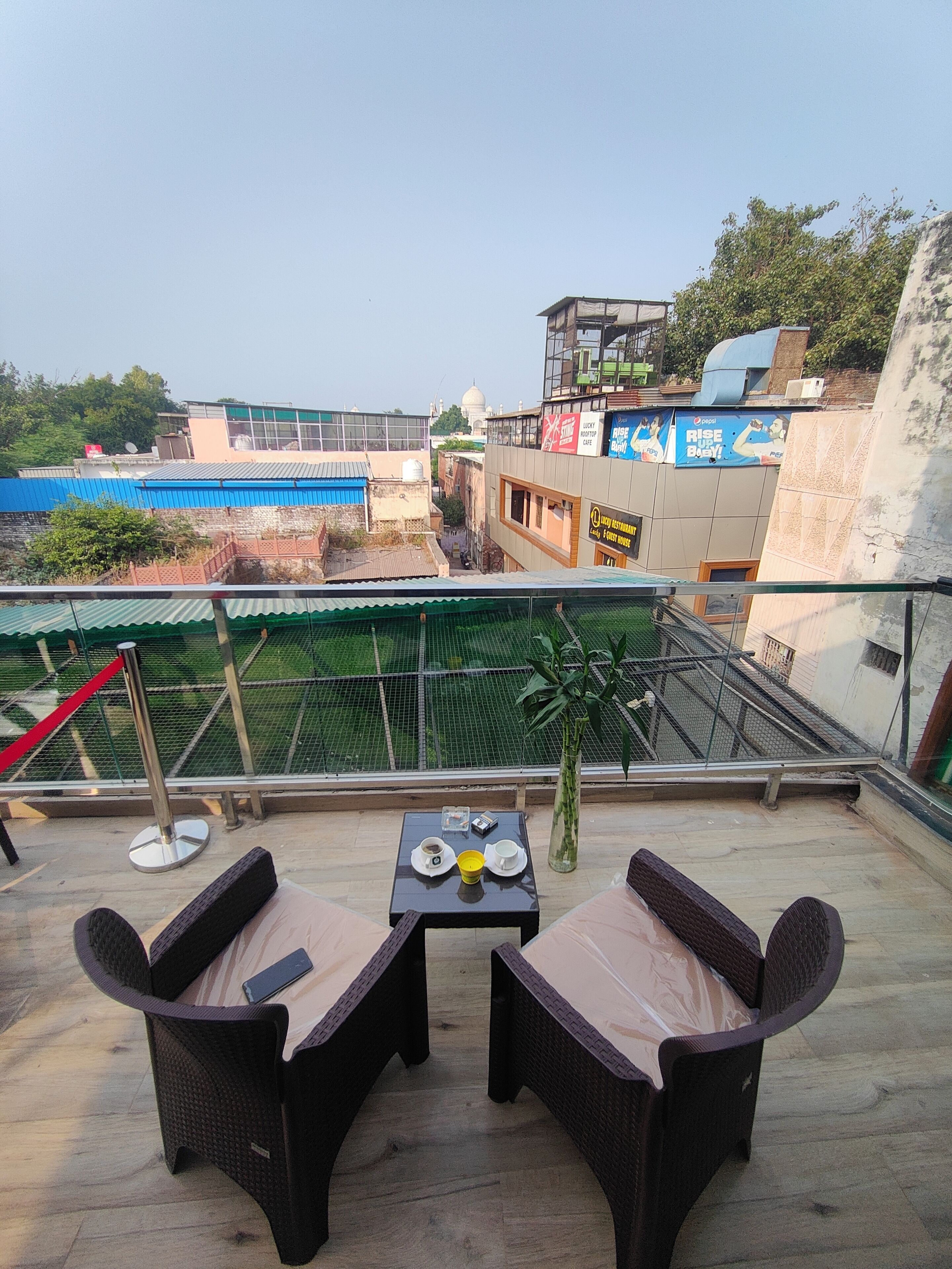 A rooftop terrace with wicker furniture, a small table with a cup and saucer, and a potted plant.