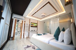 A modern hotel room with a large bed, a TV, and a glass shower area. - The Vacation Villa Agra Near Taj Mahal (Agra)