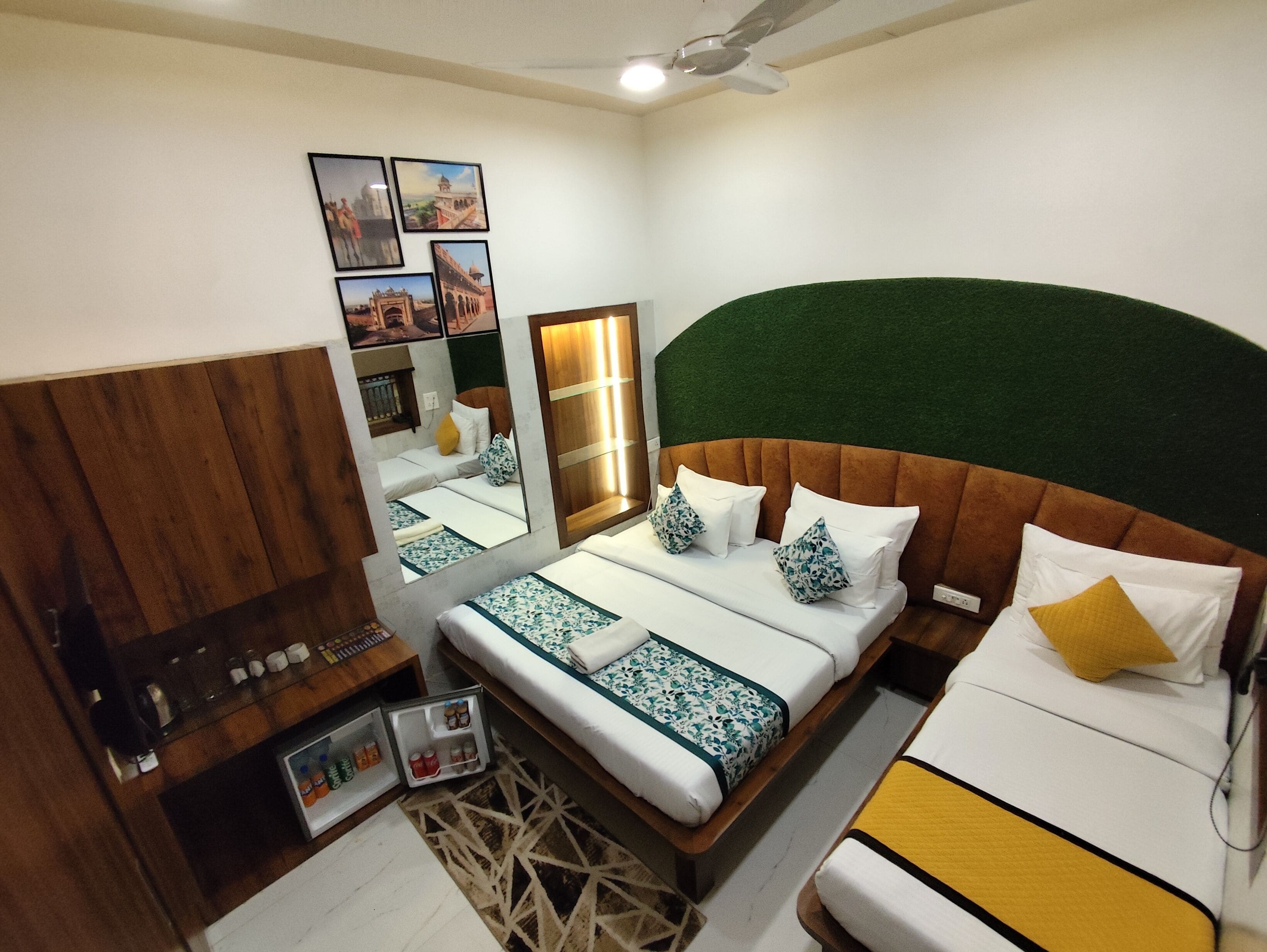 A bedroom with a bed, bedside table, mirror, and a green wall.