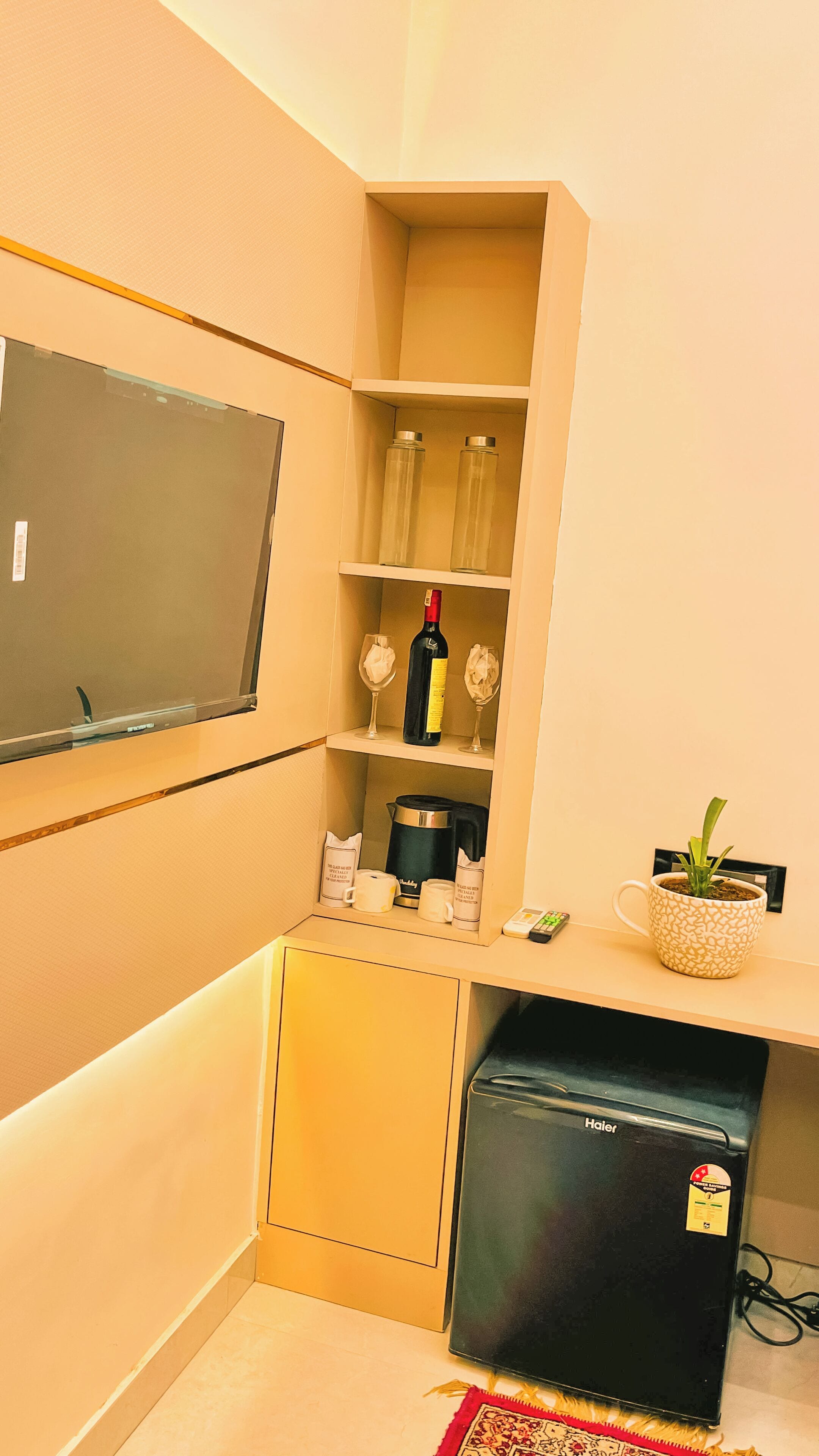 A compact kitchen with a refrigerator, a microwave, a coffee maker, and a wine bottle on the shelf.