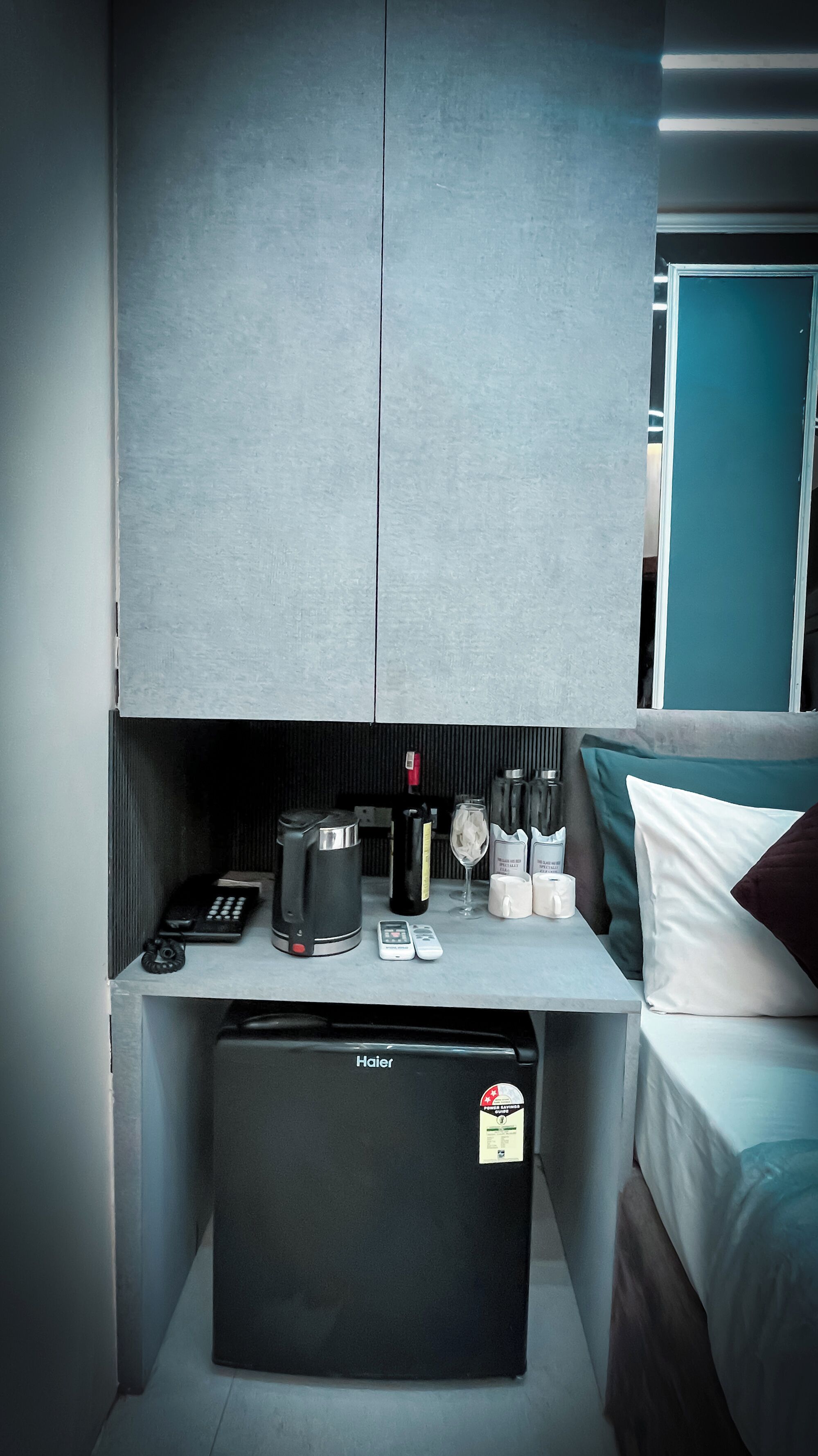 A compact hotel room with a kitchenette, a bed, and a window.