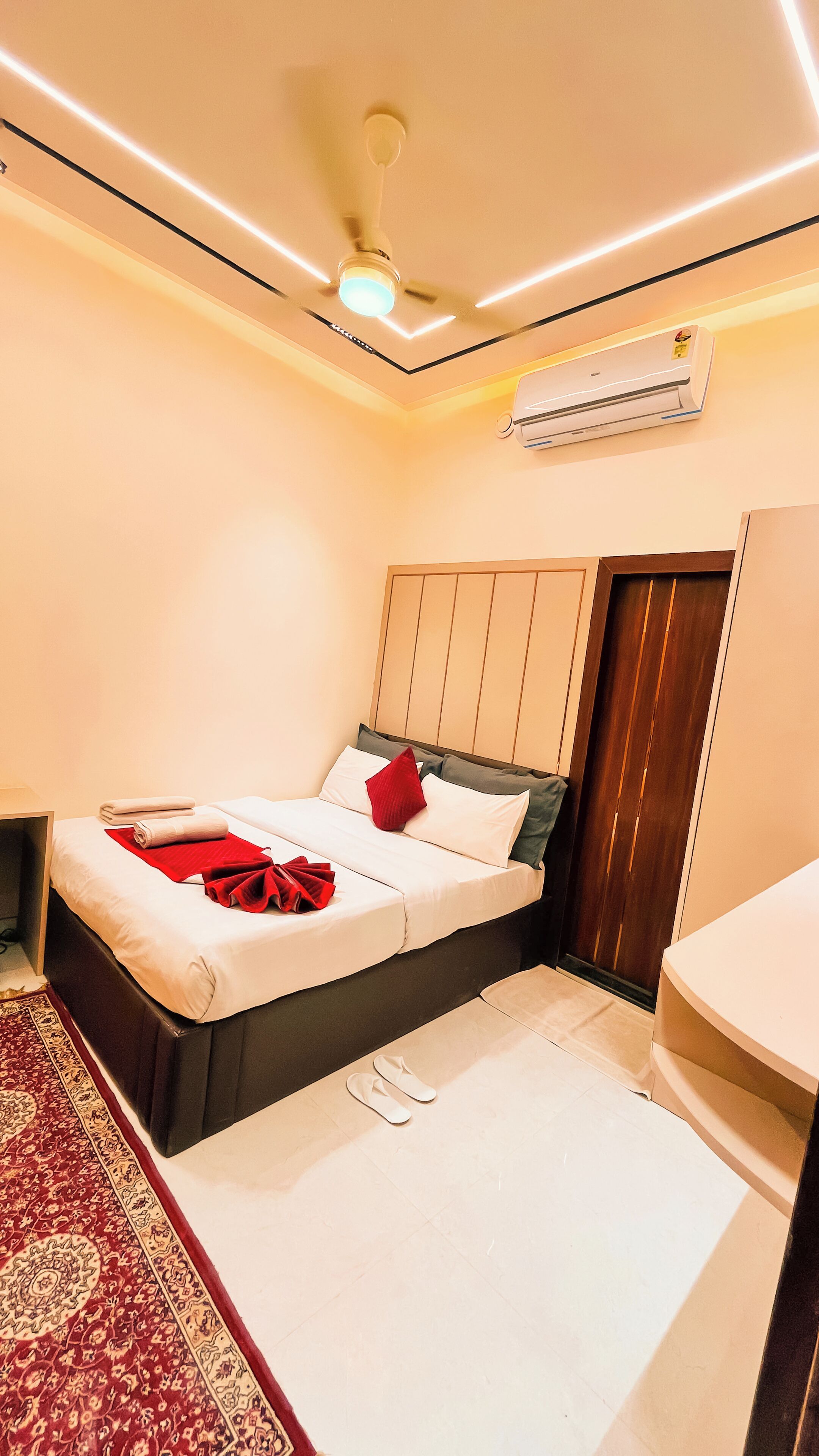 Une chambre d’hôtel avec un lit, un ventilateur de plafond, un appareil de climatisation et une petite salle de bain.