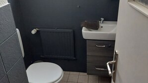 Et lille badeværelse med toilet, vask og et håndklæde hængende på væggen.