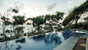 Una piscina con vista sul mare e sugli alberi.