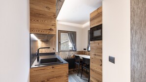 Une cuisine compacte agrémentée de touches de bois, avec un évier, une fenêtre avec des rideaux et un four à micro-ondes.