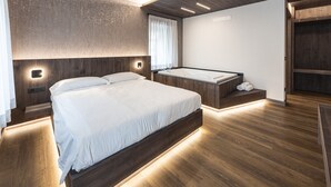 Une chambre moderne avec un grand lit, une baignoire intégrée et un plancher en bois.