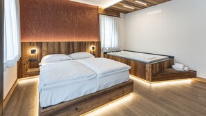 Ein modernes Schlafzimmer mit einem hölzernen Bett, einer eingebauten Badewanne und Holzboden.