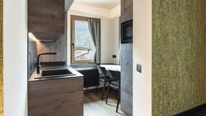 A compact kitchen with a built-in stove, a window with a view, and a dining area with a chair.