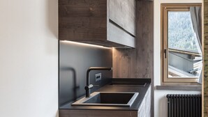 A modern kitchen with wooden cabinetry, a built-in sink, and a window overlooking a snowy landscape.