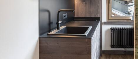 A modern kitchen with wooden cabinetry, a built-in sink, and a window overlooking a snowy landscape.