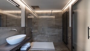 A modern bathroom with a large white sink, a glass shower enclosure, and a walk-in shower.
