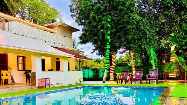 A swimming pool with inflatable toys, a house with a balcony, and outdoor furniture.