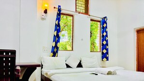 A single bed with white bedding, a wooden nightstand, and a chair.