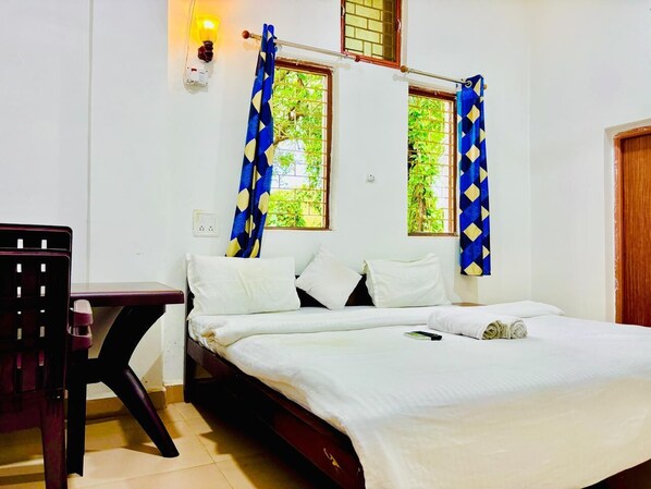 A single bed with white bedding, a wooden nightstand, and a chair.