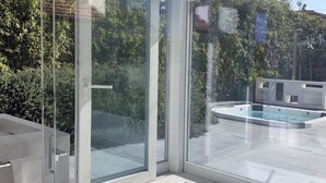 A modern bathroom with a glass shower enclosure, a bathtub, and a view of a swimming pool and greenery outside. - Elegant beachfront villa with jacuzzi, garden, and panoramic terrace. (Marzocca)