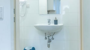 Casa de banho com lavatório branco, espelho e telefone.