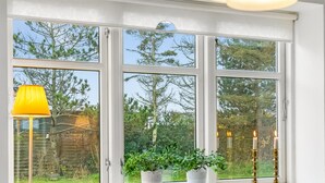 Ein Zimmer mit großem Fenster, weißen Möbeln und einer gelben Lampe.