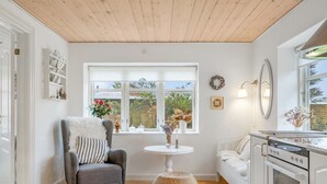 Eine moderne Küche mit weißen Schränken, einem eingebauten Ofen und einem Essbereich mit rundem Tisch und Stühlen.