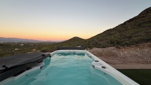Ein Whirlpool mit freiem Blick auf eine gebirgige Landschaft bei Sonnenuntergang.