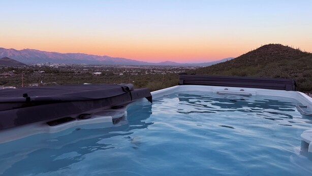 Ein Whirlpool mit Blick auf eine Stadt und Berge bei Sonnenuntergang.