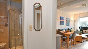 Et moderne badeværelse med en glasvægs brusekabine, toilet og et spejl på væggen.