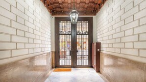 A hallway with white brick walls, a wooden ceiling, and a black gate with a metal handle. - Paseo de Gracia 5BD and 3BTH for 10 with Terrace (Barcelona)