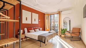 A modern bedroom with a bed, a chair, a desk, and a staircase. - Paseo de Gracia 5BD and 3BTH for 10 with Terrace (Barcelona)