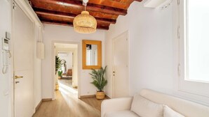 A hallway with a wooden ceiling, a white sofa, a potted plant, and a mirror on the wall. - Paseo de Gracia 5BD and 3BTH for 10 with Terrace (Barcelona)