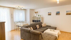 Ein modernes Wohnzimmer mit einer Eckcouch, einem Esstisch und einem kleinen weißen Tisch.
