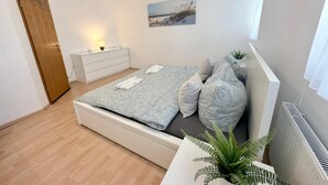 Ein Schlafzimmer mit Bett, Nachttisch, Lampe und einem Bild an der Wand.