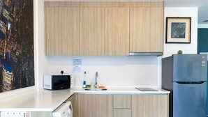 Una cocina moderna con armarios de madera, lavadora integrada, refrigerador y tostadora.