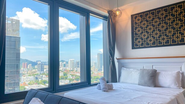 Una habitación de hotel con una cama grande, vistas a la ciudad y una obra de arte geométrico en la pared.