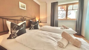 Habitación de hotel con dos camas, cada una con sábanas blancas y almohadones decorativos, un cuadro en la pared y una ventana con cortinas.
