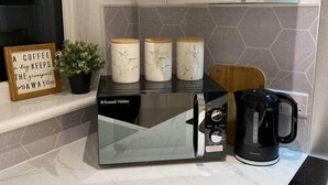 Uma cozinha com fogão embutido, máquina de café e chaleira sobre o balcão.