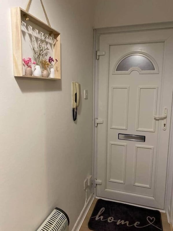 Una puerta blanca con un buzón, un teléfono en la pared y un felpudo que dice 'hogar'.