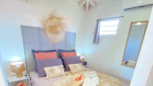 Un dormitorio con cama, mesita de noche, espejo en la pared y ventilador de techo.