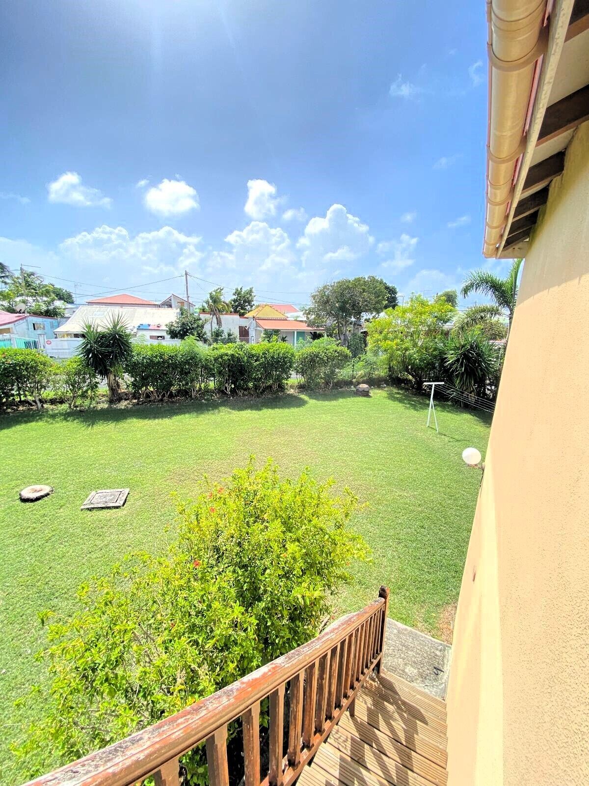 Blick auf einen gepflegten Garten mit Holzterrasse, saftigem Rasen und verschiedenen Pflanzen und Bäumen.
