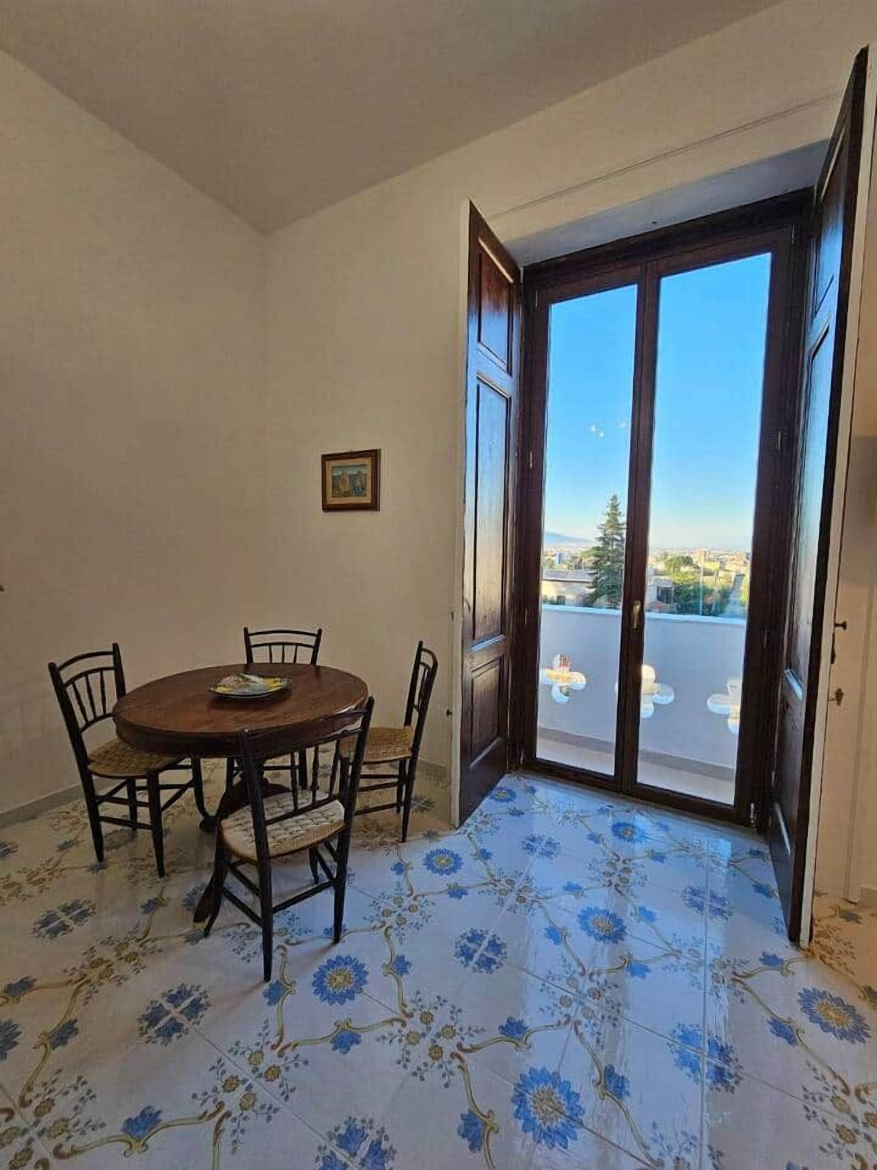 Un comedor con una mesa redonda y sillas, una puerta que da al exterior, y un suelo con diseño.