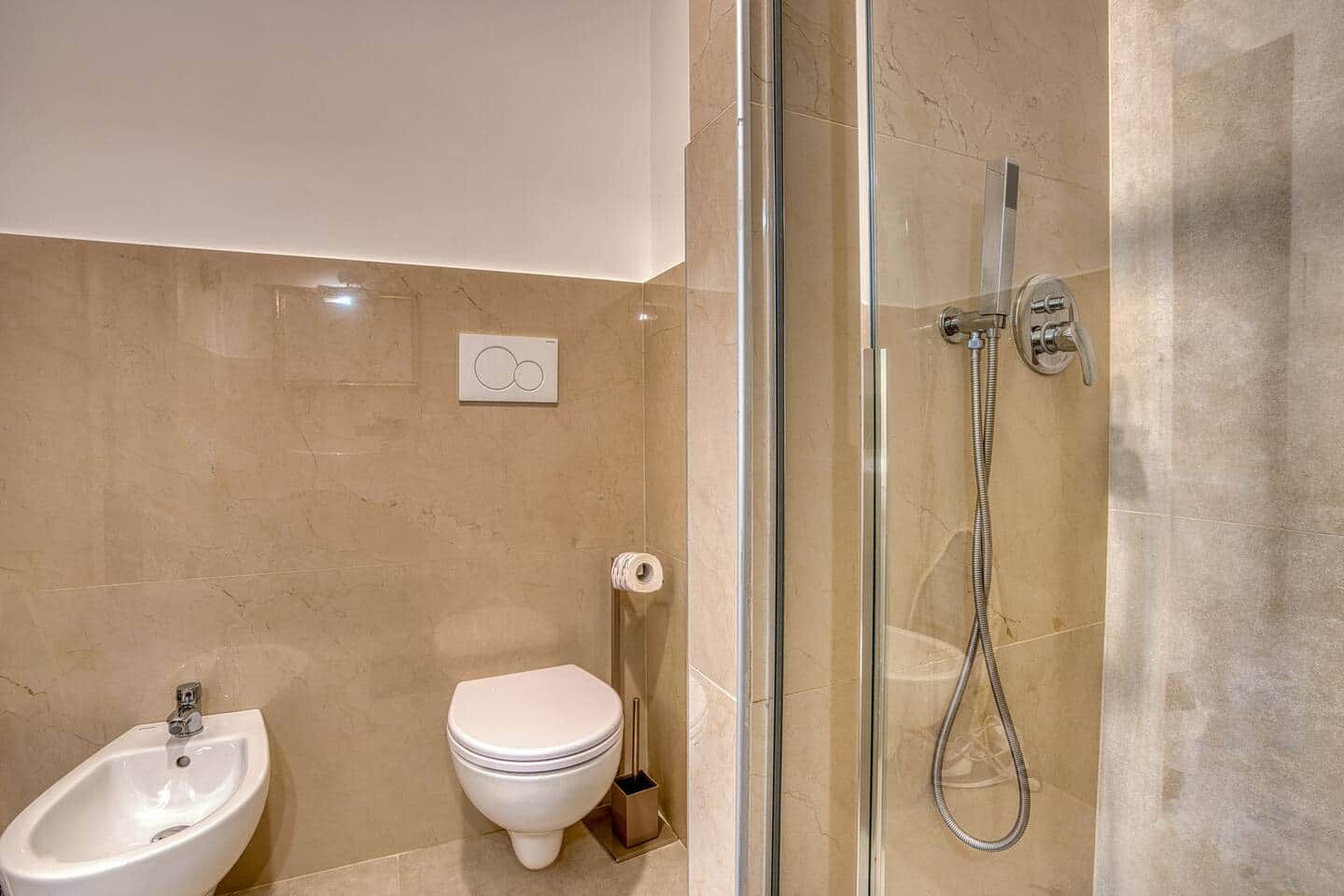 Une salle de bain moderne dotée d’une douche à parois de verre, d’un bidet, de toilettes et d’un lavabo.