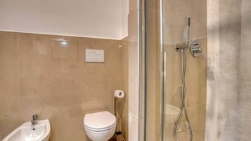 Une salle de bain moderne dotée d’une douche à parois de verre, d’un bidet, de toilettes et d’un lavabo.