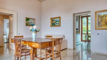 Un comedor con una mesa y sillas de madera, un jarrón con flores y dos cuadros en las paredes.